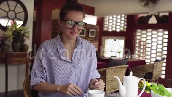 戴眼镜的漂亮女商人喝茶在咖啡馆里放松视频的预览图