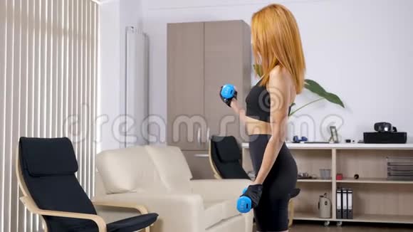 有哑铃的年轻女子在家练习运动视频的预览图
