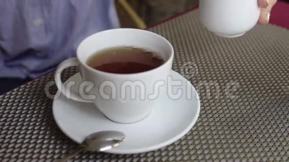 把牛奶倒入一杯茶里女人把牛奶倒进热茶里视频的预览图