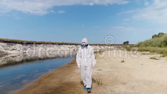 一个穿着防护服和呼吸器的人沿着干河散步视频的预览图