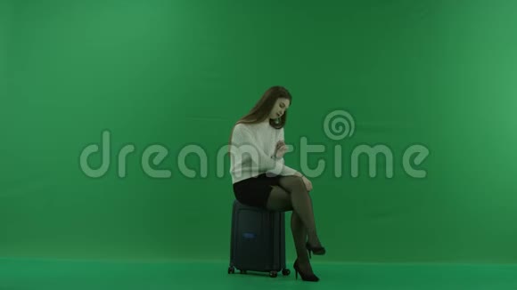 女孩坐在手提箱里在绿色的屏幕上等待着什么视频的预览图