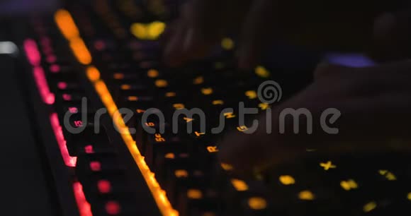 在背景模糊的黑暗环境下双手打字多色LED键盘视频的预览图
