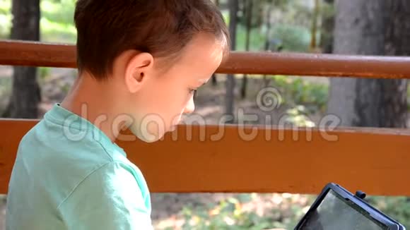 秋天公园里有平板电脑的青少年学龄前儿童小学生在阳台上玩平板电脑或者视频的预览图