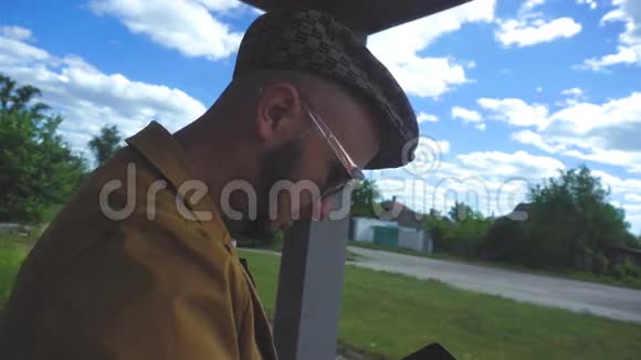 戴着胡子戴着眼镜戴着帽子的帅哥坐在云层的背景下视频的预览图