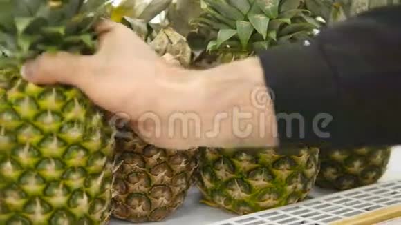 男手在超市挑选菠萝从杂货店柜台拿菠萝的人挑选一个视频的预览图
