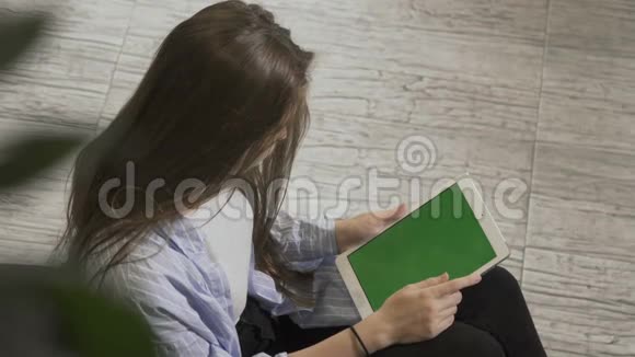 有平板电脑的漂亮女孩坐在扶手椅上视频的预览图