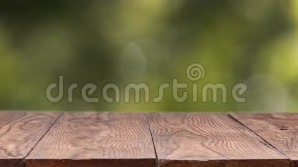 绿色的叶子在风中一个自然模糊的背景与一个木制的旧固定桌子在一个夏天阳光明媚的日子慢慢视频的预览图