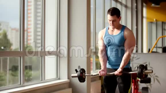 健身馆里的健美运动青年男子用杠铃进行手臂训练视频的预览图