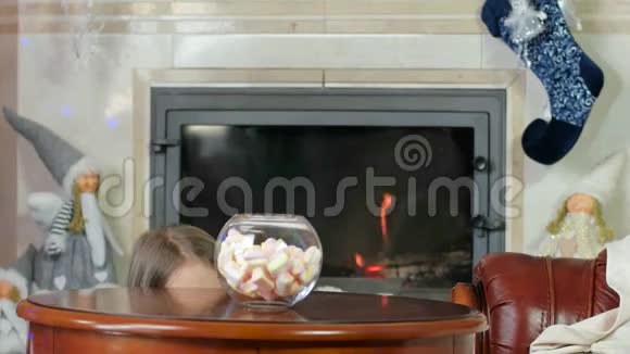 孩子们偷糖果小女孩躲在桌子下面看着外面拿糖果棉花糖孩子们狡猾地看着视频的预览图