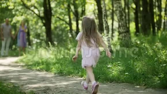 阳光明媚的一天一个金发小女孩正在公园里奔跑慢镜头视频的预览图