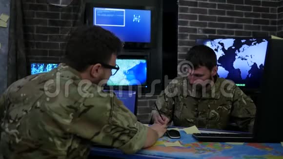 两名穿制服的严肃士兵战争中心监控室为笔记本电脑工作搜索安全系统视频的预览图