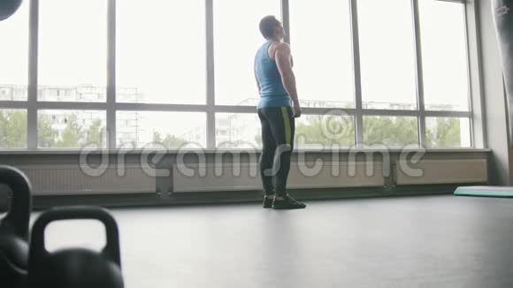健身俱乐部肌肉男在窗户附近做热身运动视频的预览图