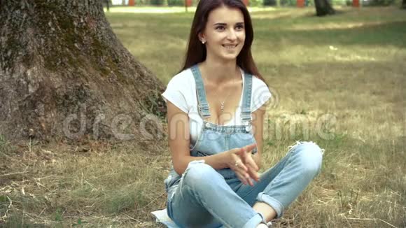 可爱的女孩坐在草地上的公园里拿着礼物视频的预览图