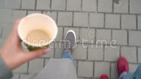 俯视男女腿漫步人行道喝咖啡的女人视频的预览图