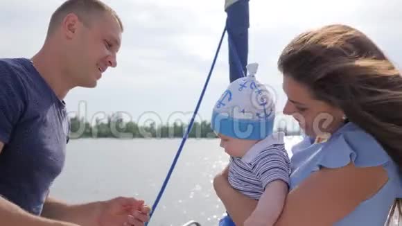 好心情友好的一家人去河边度假年轻的爸爸妈妈和宝宝在船上玩视频的预览图