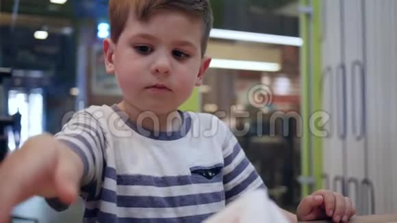 可爱的饥饿男孩在街头咖啡馆用有害的食物来消除饥饿小男孩在餐桌上吃汉堡胃口很好视频的预览图