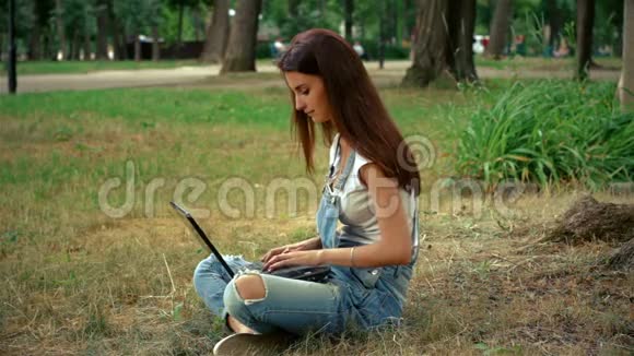 穿针引线的女孩坐在树旁时会在你的笔记本上印上指纹视频的预览图