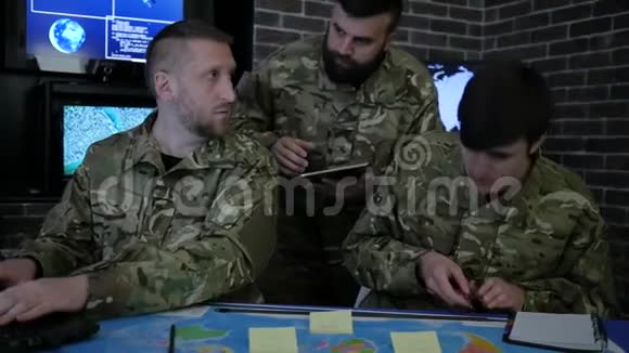 穿制服的士兵在数字平板电脑笔记本电脑和笔记本电脑上工作在军事基地讨论攻击战争中心视频的预览图