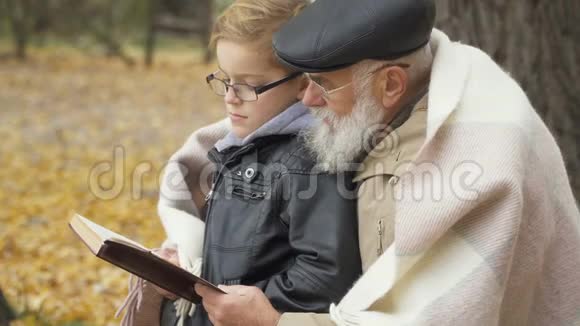 祖父和孙子在秋天公园读这本书视频的预览图