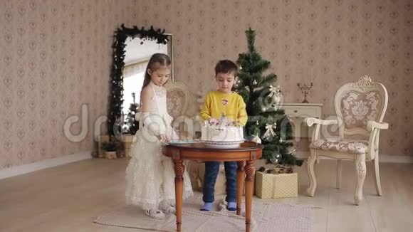 小姐姐和弟弟装饰圣诞蛋糕圣诞节附近宽敞明亮的房间里有漂亮的孩子视频的预览图
