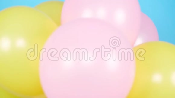 快乐的女人带着五颜六色的气球在蓝色背景上玩得很开心视频的预览图