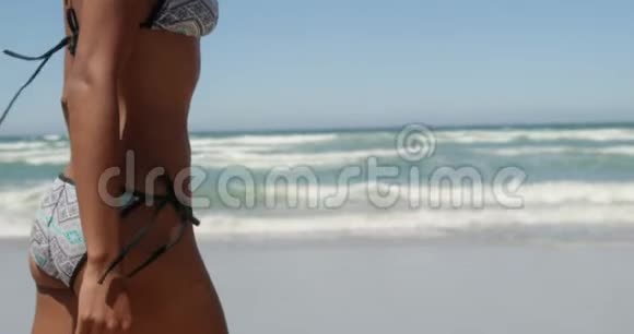 在阳光4k的海滩上穿比基尼的年轻非洲裔美国妇女的侧面景色视频的预览图