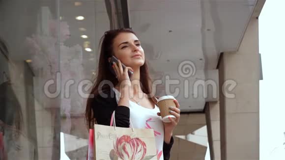 漂亮的年轻女孩带着价值在商店附近的包裹在电话里交谈视频的预览图