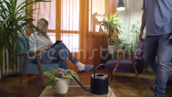 现代家庭女性从平板电脑上阅读的男人浇水和喷洒植物视频的预览图