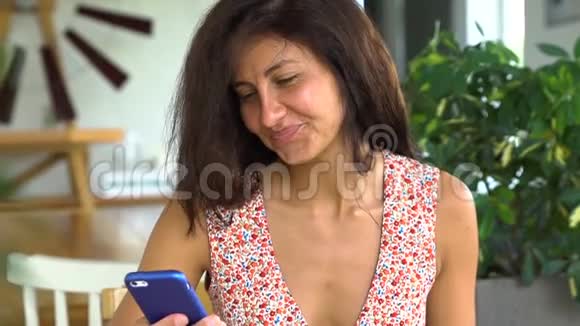 年轻的女人使用智能手机和微笑和朋友聊天视频的预览图