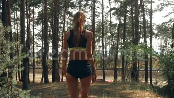 年轻苗条的运动女孩穿着短短裤臀部穿过树林视频的预览图
