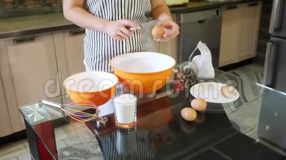 女人的手在碗里砸鸡蛋分离蛋黄和蛋白质视频的预览图