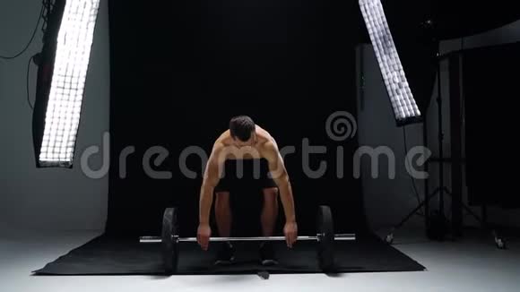男人正在用杠铃做运动在演播室里在黑色背景上做交叉训练视频的预览图