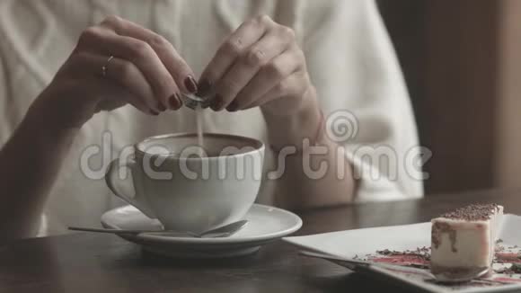 女人把糖倒在咖啡馆的杯子里视频的预览图