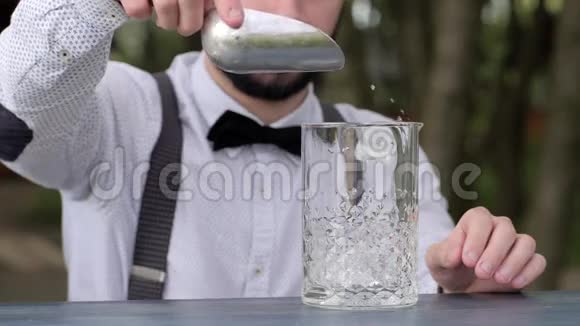 酒吧桌上的酒保把透明的冰块放进玻璃里酒吧服务员把冰块放进新鲜空气里的玻璃里视频的预览图