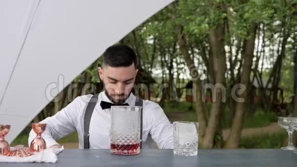 肖像酒保把冰加到酒吧柜台上的一杯酒里酒保把冰放进酒杯里拿着餐巾视频的预览图