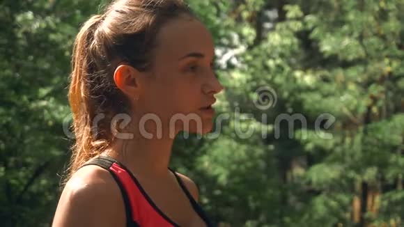 年轻的性感运动女孩站在树林里脸上湿漉漉的脸颊上的水滴流下视频的预览图