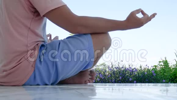 坐在瑜伽莲中的人在草地上的绿草上摆姿势沉思视频的预览图