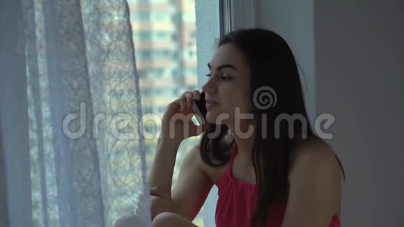 戴着牙套的女孩结束了电话里的谈话望着窗外视频的预览图