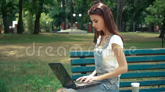 一个漂亮的黑发女人坐在长凳上手提电脑视频的预览图