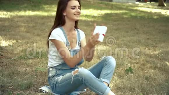 布鲁内特坐在草地上拿着一个带蝴蝶结的礼品盒视频的预览图