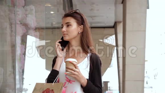 女孩看着店面手里拿着一杯咖啡打着电话视频的预览图