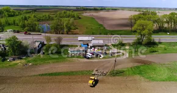 一辆拖拉机在高速公路附近的田野上的航镜头视频的预览图