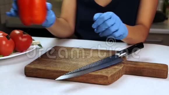 在木板上女手戴着橡胶手套切着红色的甜椒视频的预览图