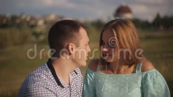 恋爱中的幸福夫妇在约会时开怀大笑城市背景下绿茵草地上的男人和女孩视频的预览图