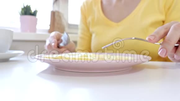 女人坐在桌子旁吃着一个带着一个民间和一把刀的小面包在家里或家里喝咖啡或茶视频的预览图