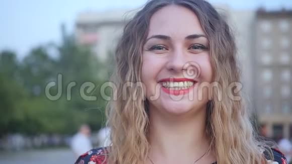 一个快乐的微笑的女人在城市的街道上热烈地笑可爱的白种人女子夏季特写肖像视频的预览图