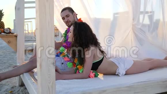 爱情浪漫的情侣一个异国情调的假期年轻人的暑假女孩穿着夏威夷雷衫在男人的脖子上视频的预览图