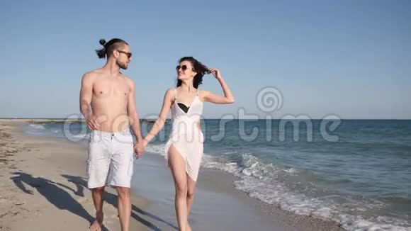 情侣赤着脚走在沙滩上浪漫地走在海边朋友在旅行中玩得开心在爱的人面前调情视频的预览图