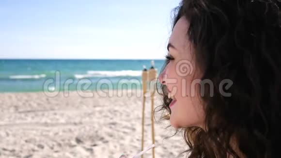在海滩上留着卷发的快乐女人女人打招呼女人喝鸡尾酒视频的预览图