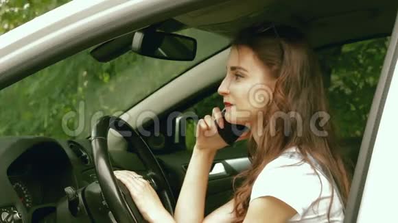年轻的黑发女人开车时打电话视频的预览图